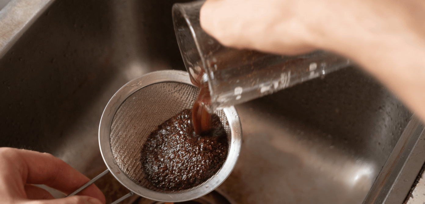 Alter Kaffeesatz gießt in Küchensieb über Waschbecken